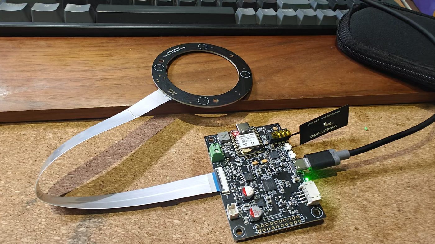 reSpeaker 四麦圆环经 FFC 接到 Flex 载板，USB-C 供电，2.4 GHz 天线伸出 — DoA 来自这块芯片，不是神经网络。