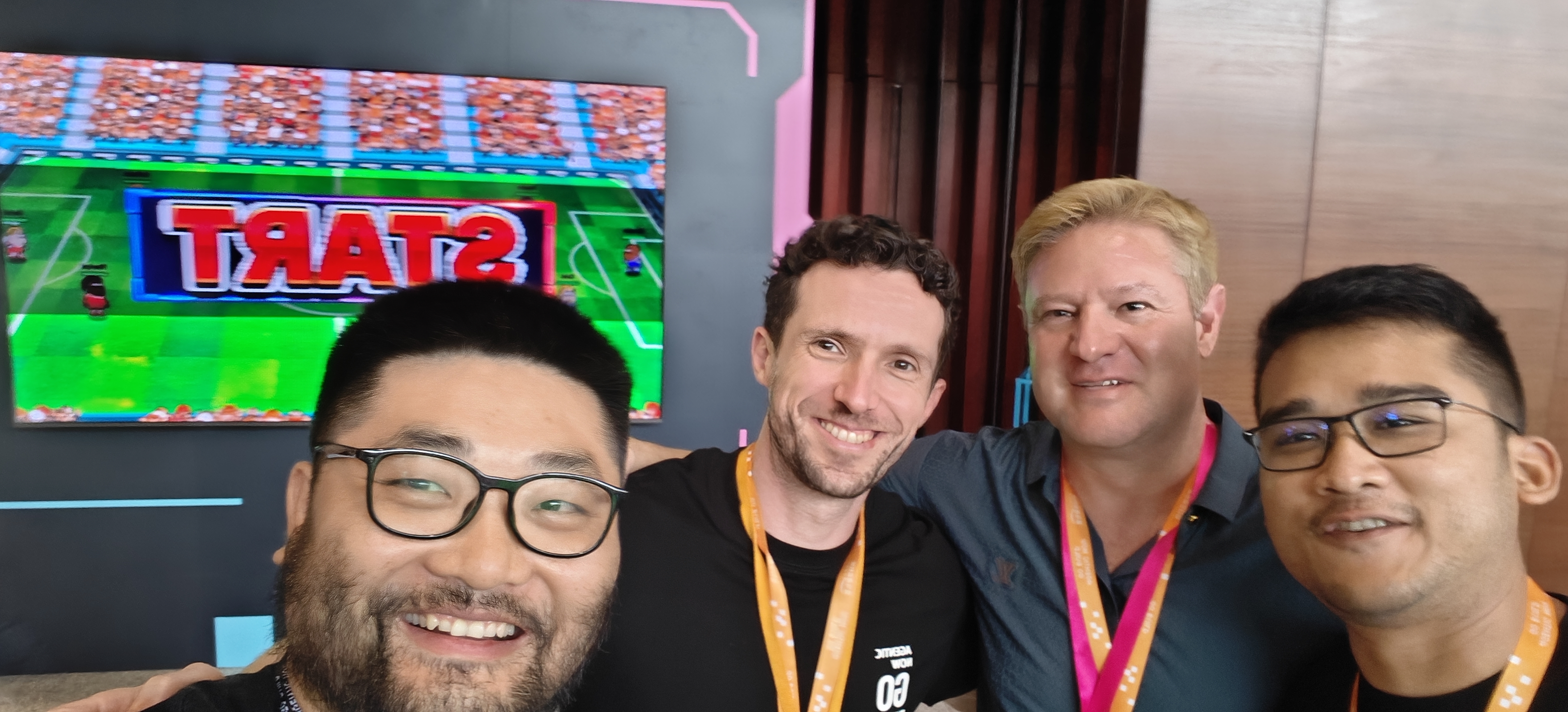 上海 Summit — 与 Agentic Football 作者合影，身后大屏是像素球场的 START 画面